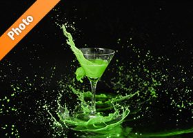 カクテルグラスと緑色の液体が弾ける写真・フォト素材